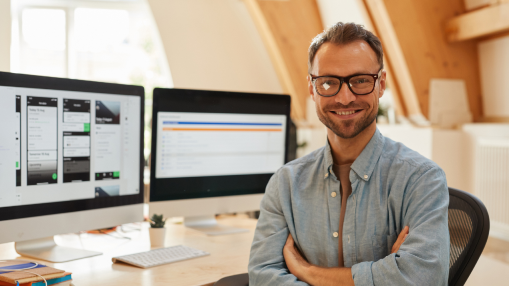 A web developer sitting at his desk with multiple monitors displaying website designs, representing WordPress Development Services.